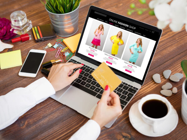 person's hands near a computer screen looking at a product page for a fashion site and holding a credit card