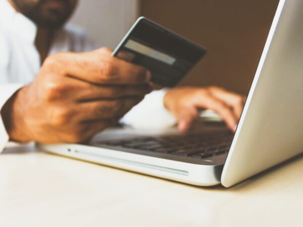 person on a computer holding a credit card