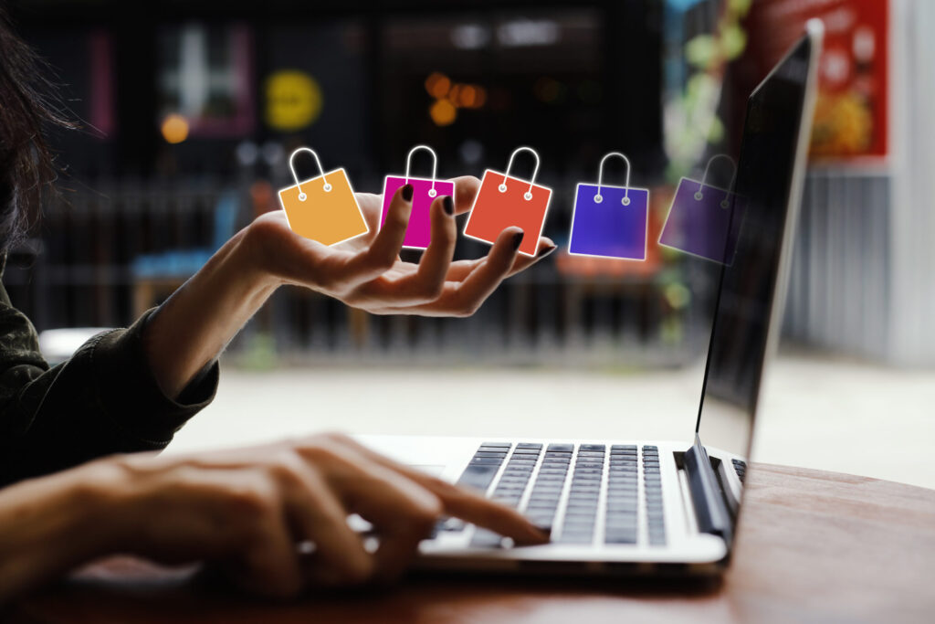 woman hands holding shopping bags and pointing at a laptop keyboard