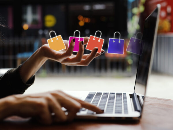 woman hands holding shopping bags and pointing at a laptop keyboard